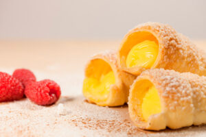 Cañas fritas rellenas de nata con fruta de la pasión, piña y salsa de cítricos